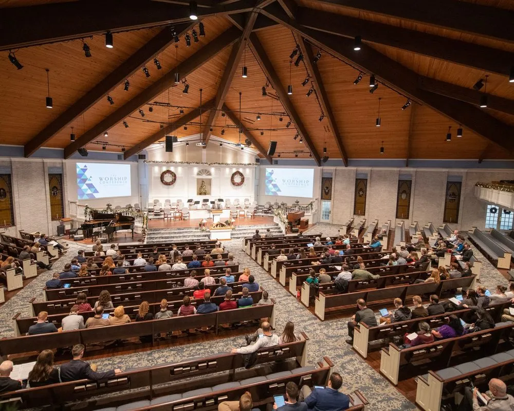 A full sanctuary with a wooden ceiling during a Sunday service